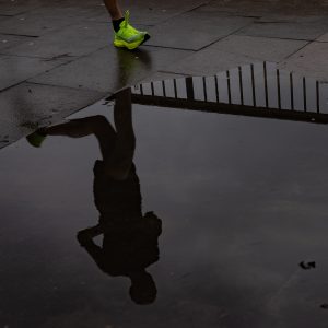 A runner's reflection in a street puddle