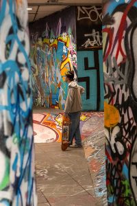 A skateboarder in the graffiti covered tunnels